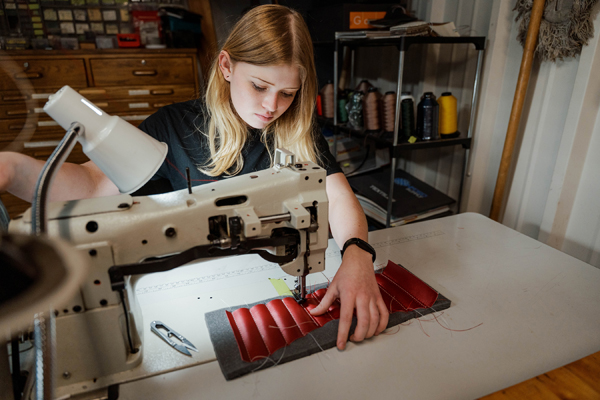 Morgan Moravec sews a car interior panel as part of a restoration school project.